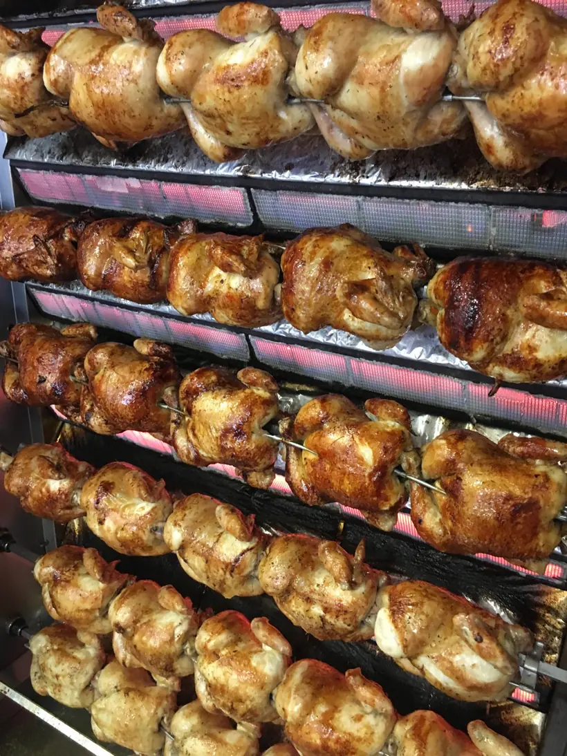 Asador de Don Pollo lleno de pollos dorándose en el espetón